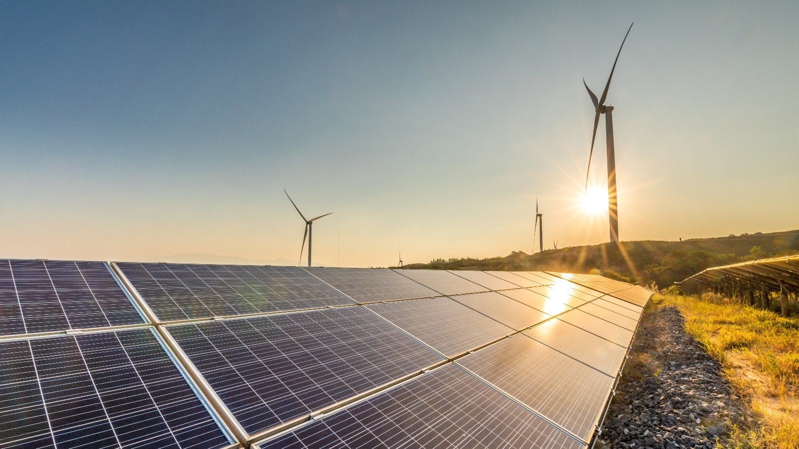 Field of solar panels and a wind turbine.