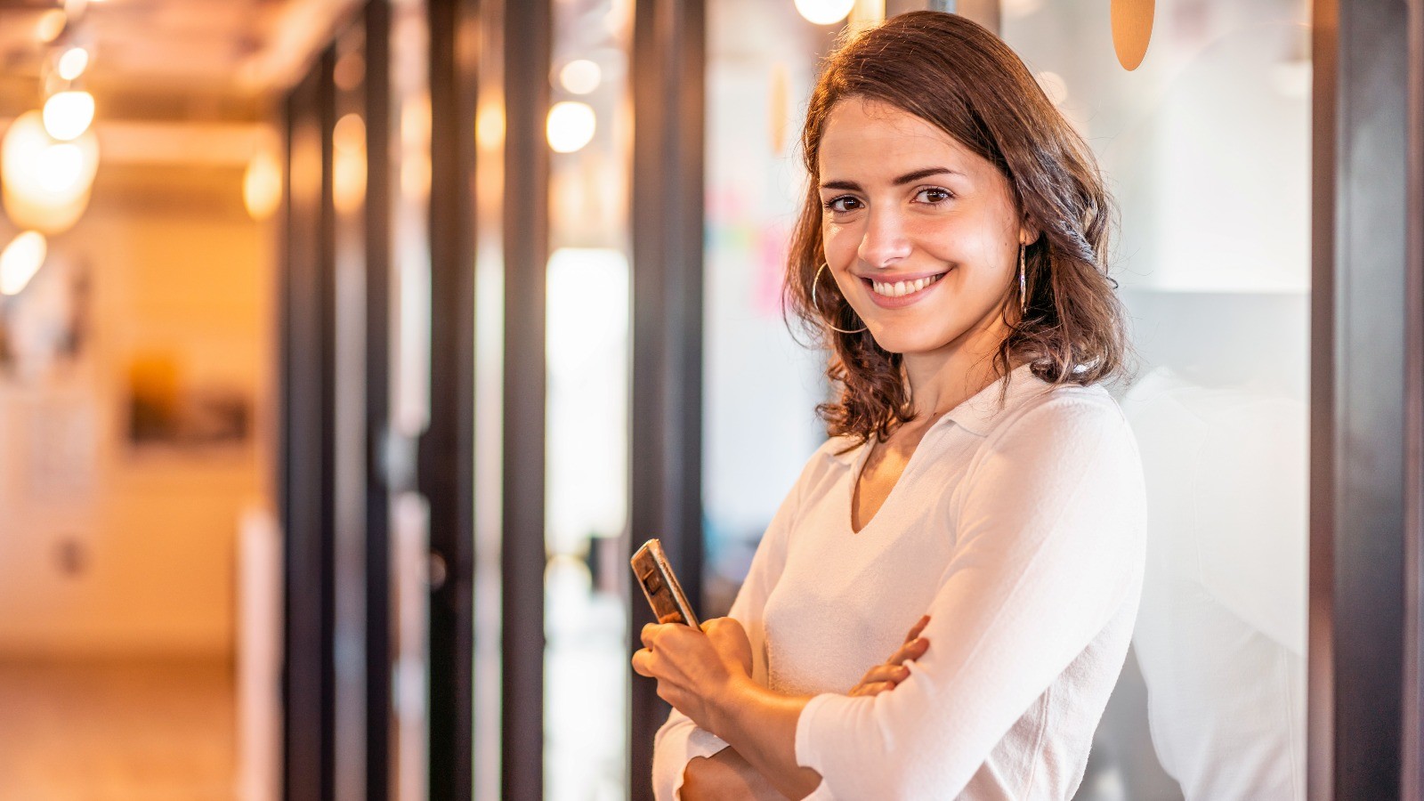 a woman smiling at the camera holding her phone