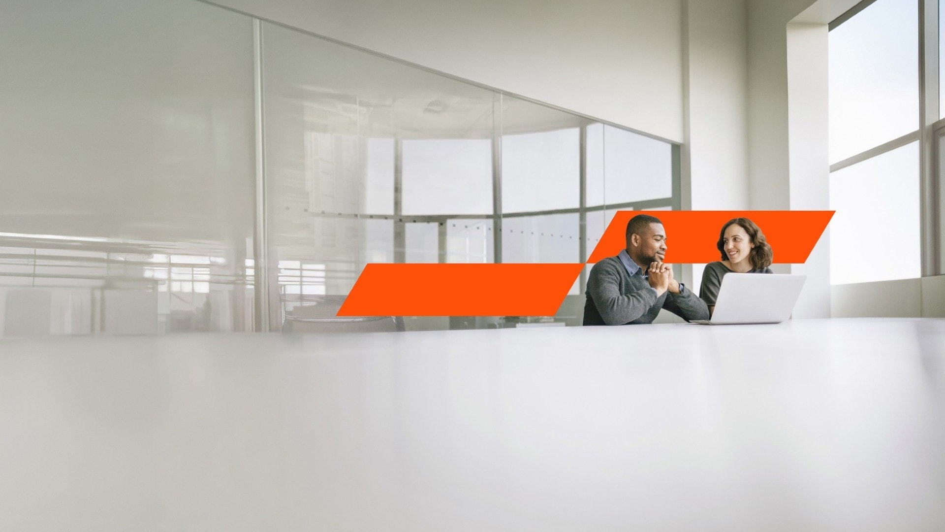 Two people sitting at a table, chatting in an office space.