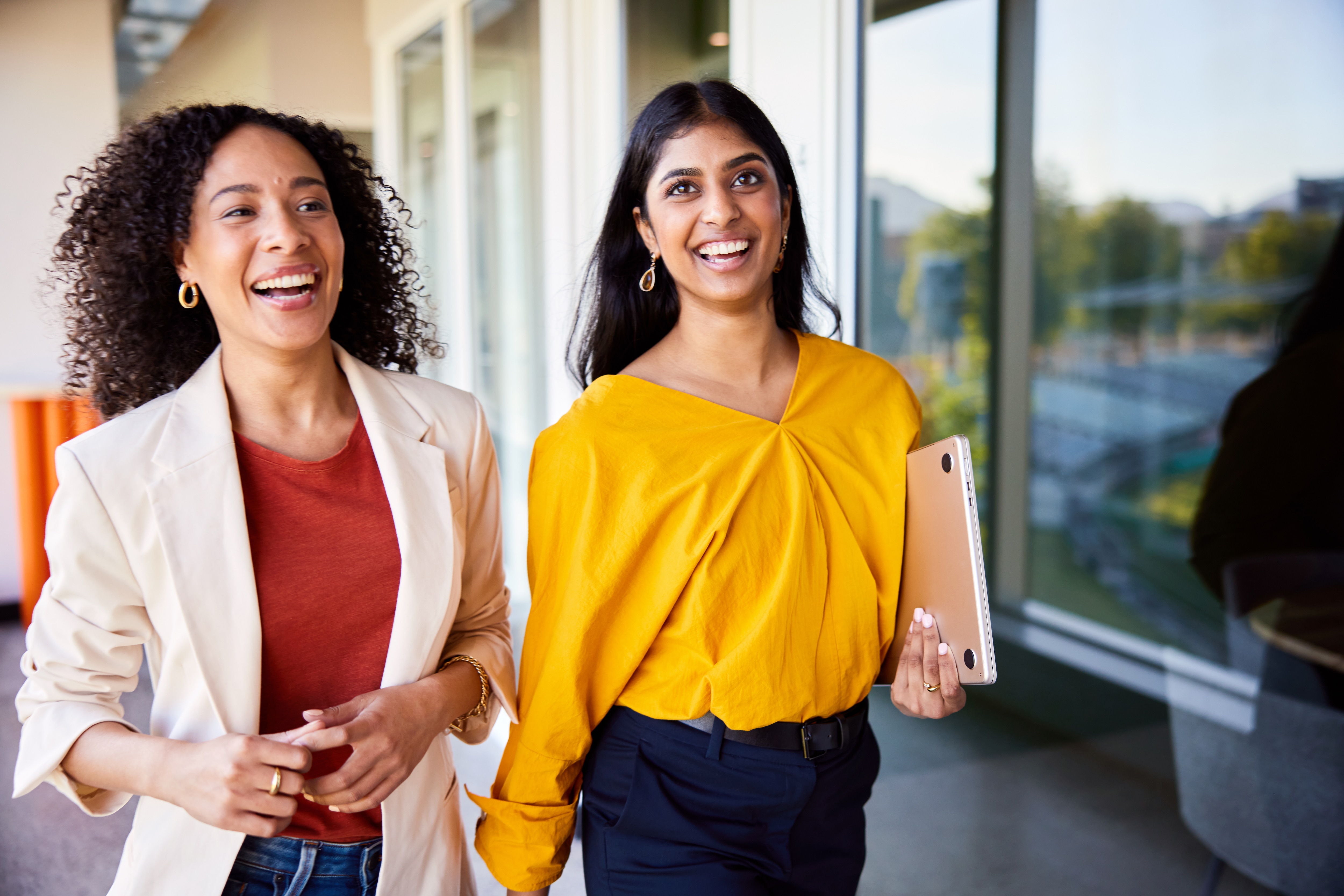 two women walking and laughing together 